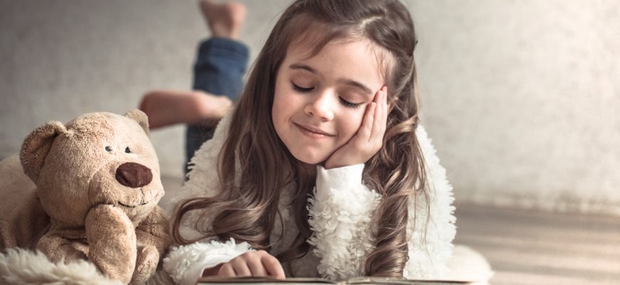 little girl reading book with teddy bear floor concept relaxation friendship 1 - Мрії дитини своїми руками: в Івано-Франківську стартував конкурс із благодійною метою. Відео - rai.ua